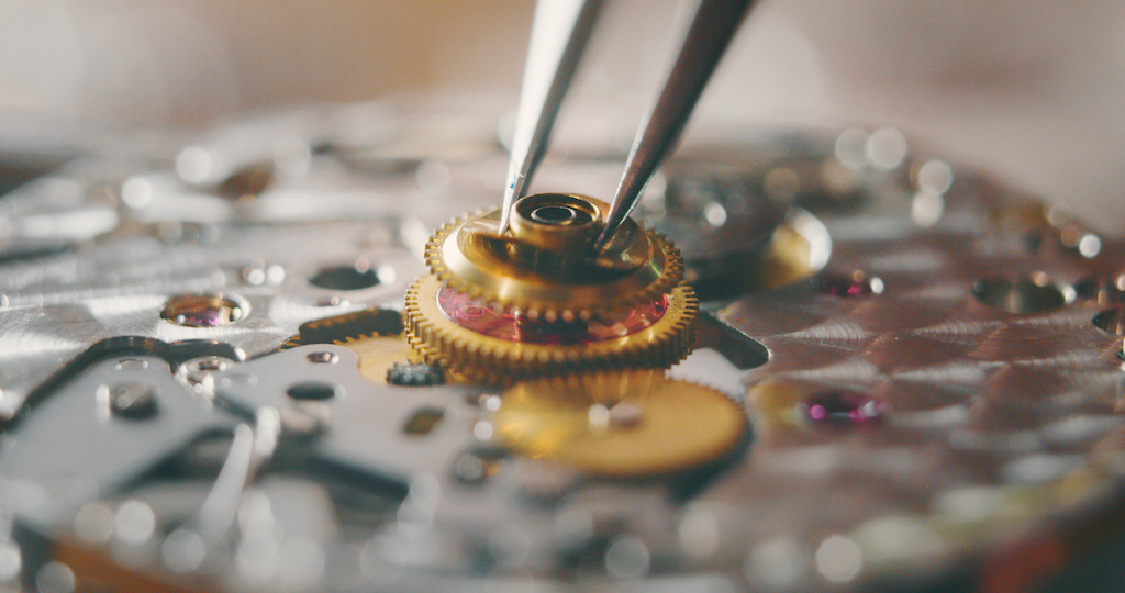 Portrait close up of a professional watchmaker repairer working on a vintage mechanism clock in a workshop. Expert watch repair. 