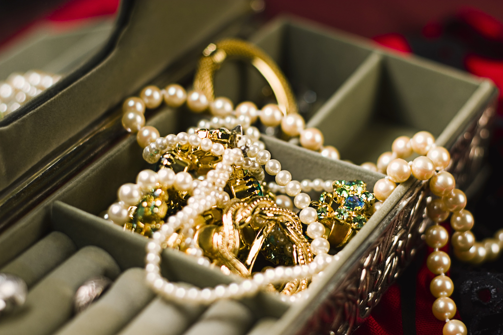 A jewelry box overflowing with pearls, gold, and more, in need of Jewelry repair service.