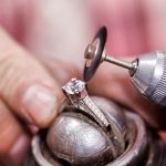 A jewelry is polishing a diamond ring for jewelry repair service.