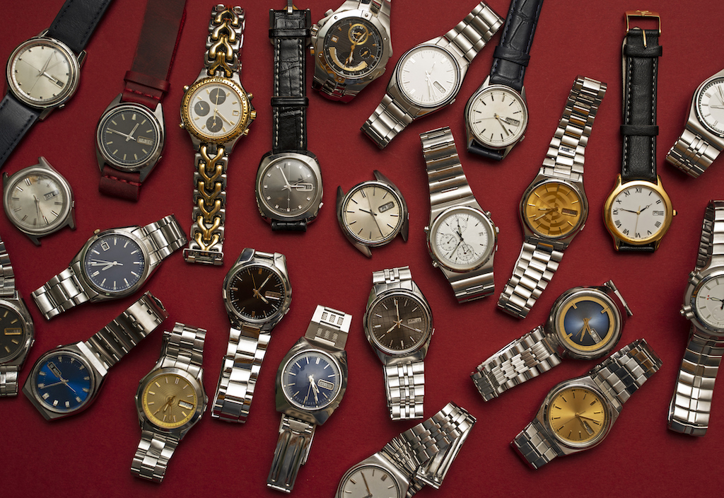 Group of different wristwatches on red background. Watch repair service.