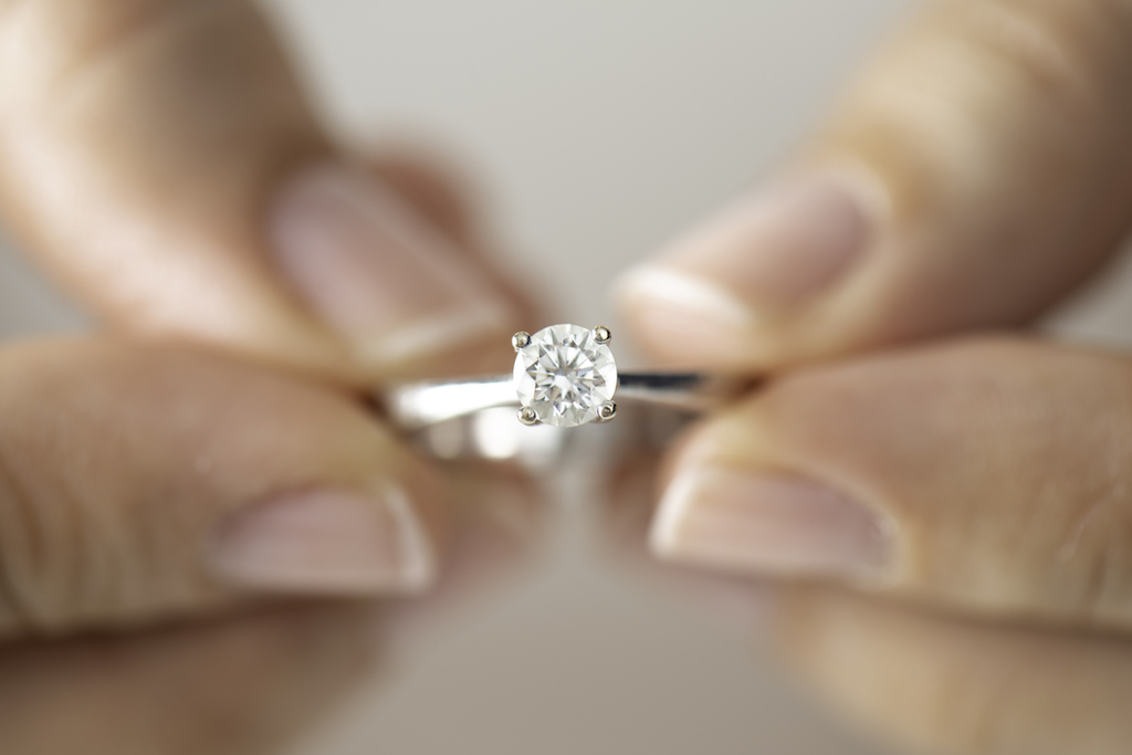 Woman holding engagement ring in need of Wedding Ring Engraving.