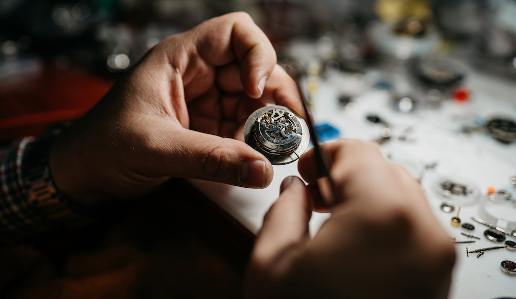 Person working on watch repair in workshop. | Engagement Rings & Wedding Bands