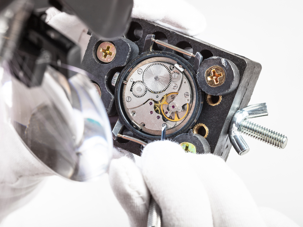 Close up shot of watch repairman working on luxury watch. 