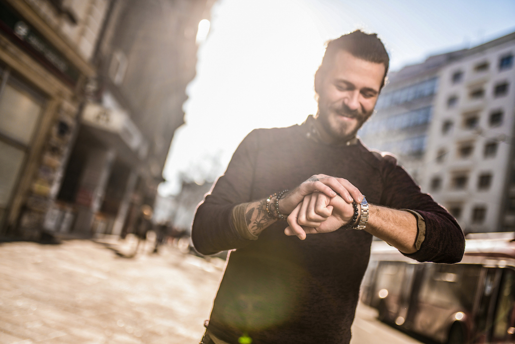 Happy man walking down street checking time. | Omega Watch Repair
