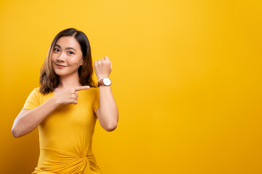 Happy woman pointing at watch thanks to Luxury Watch Restoration. 