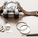 Omega watch repair, mechanics and tools on table.